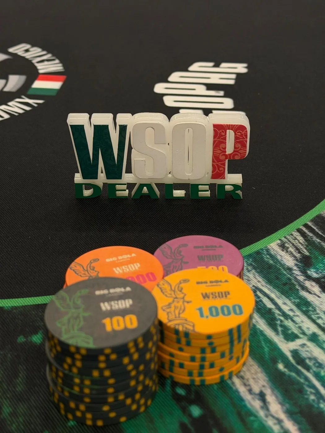 Botón de dealer de la WSOP junto a torres de fichas con el logo del evento